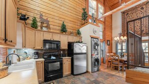 Una cucina con mobili in legno, un frigorifero in acciaio inossidabile, un forno a microonde e un lavandino.