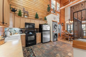 A kitchen with wooden cabinets, a stainless steel refrigerator, a microwave, and a sink. - Ozark Hideaway Cabin • 2BR/2BA • Sleeps 6 • Jetted Tub • Covered Deck • Resort Pool (Branson)