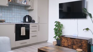 A modern kitchen with a built-in oven, a coffee maker, and a microwave. - Brand New, Beautifully Designed Apartment in the Heart of Fulham (London)