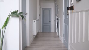 A hallway with a light-colored wooden floor, white walls, and a door at the end. - Brand New, Beautifully Designed Apartment in the Heart of Fulham (London)