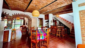 A dining area with a brick ceiling, wooden chairs, and a colorful tablecloth.