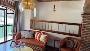 A room with a brick ceiling, a leather sofa with cushions, a small round table, and a hanging wicker light fixture.
