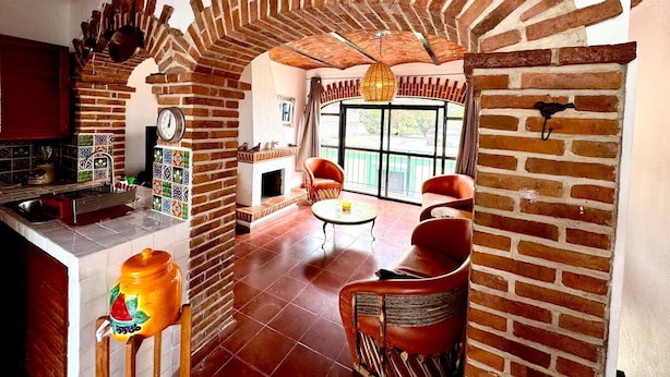 A cozy interior with a brick fireplace, a dining area, and a kitchen with tiled backsplash.