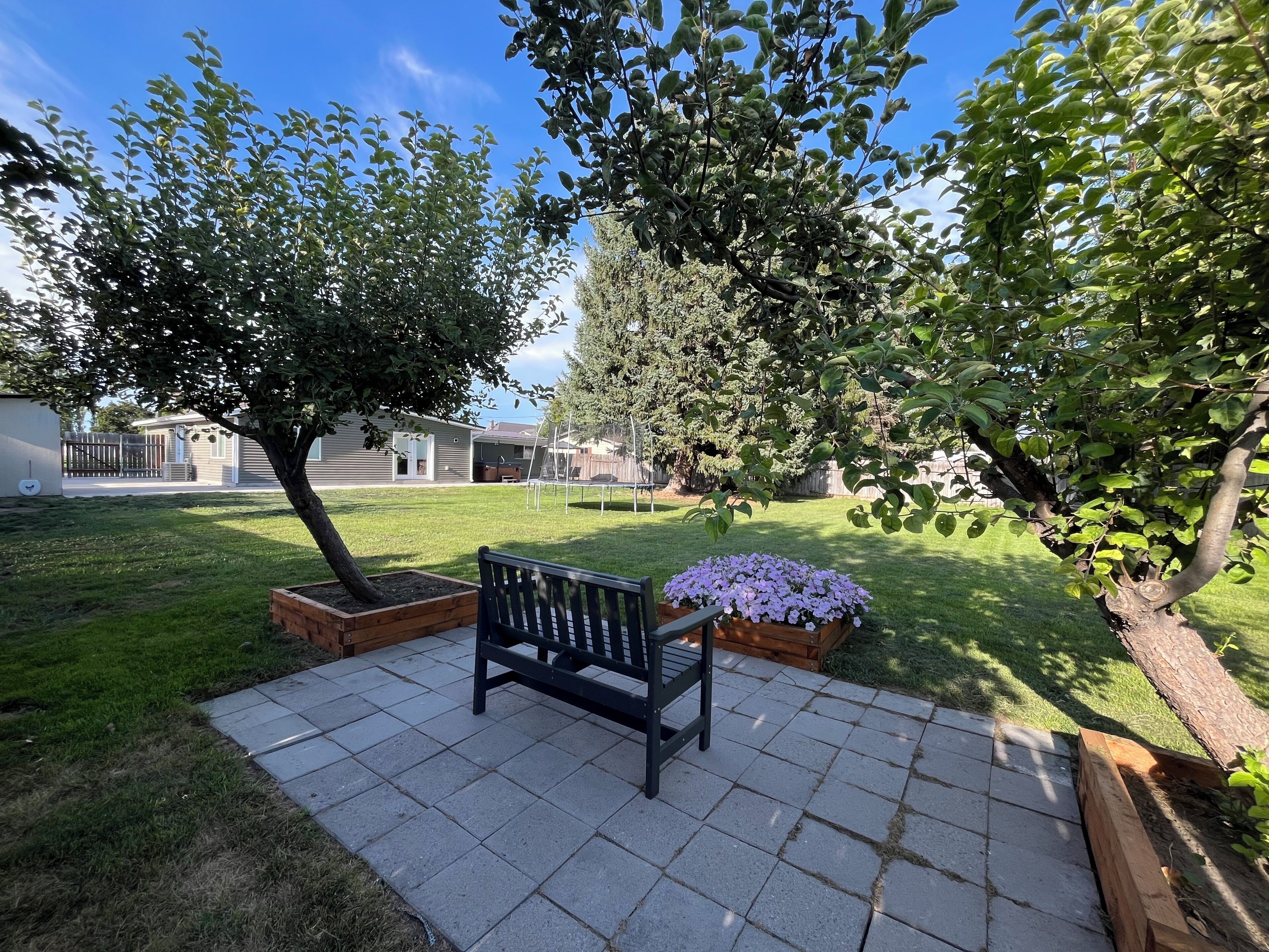Un espace extérieur aménagé avec un banc, un parterre de fleurs et une pelouse.