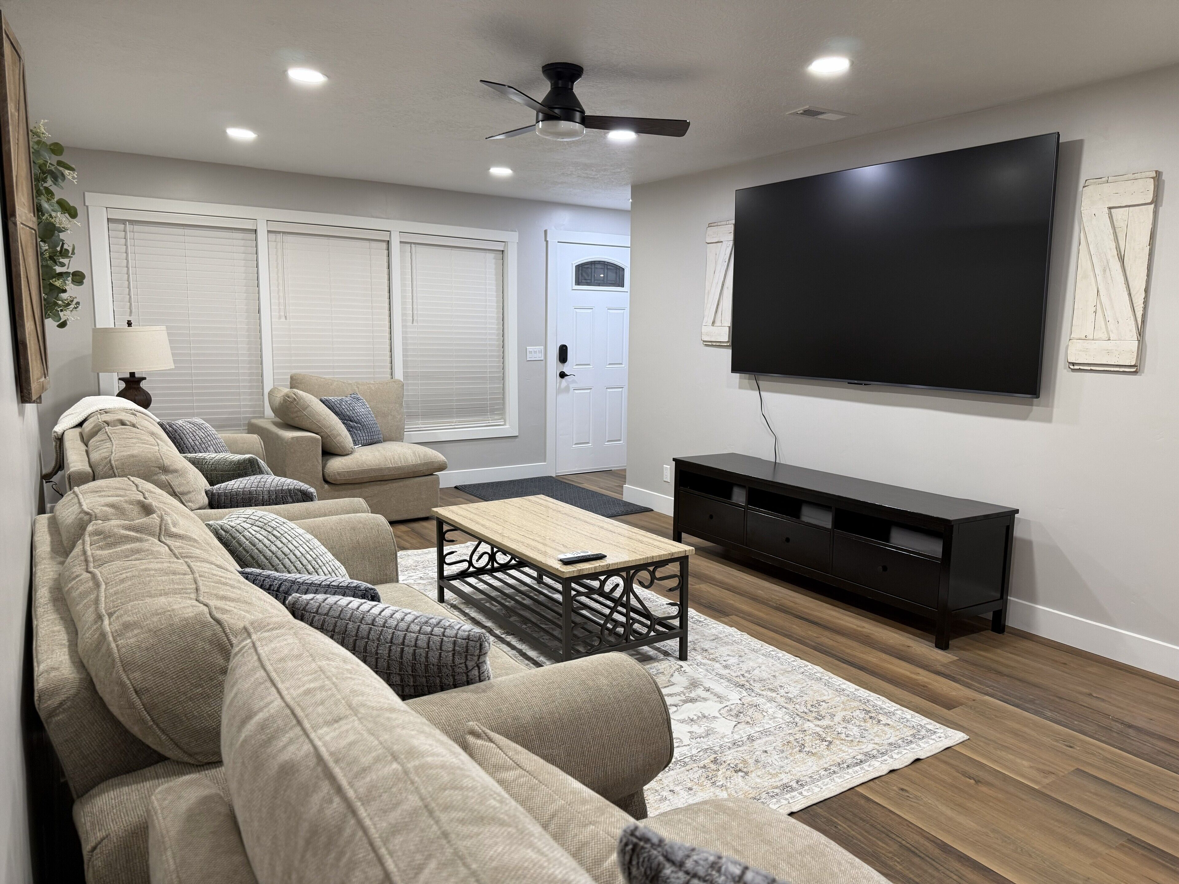 A living room with a sofa, coffee table, TV, and a ceiling fan.