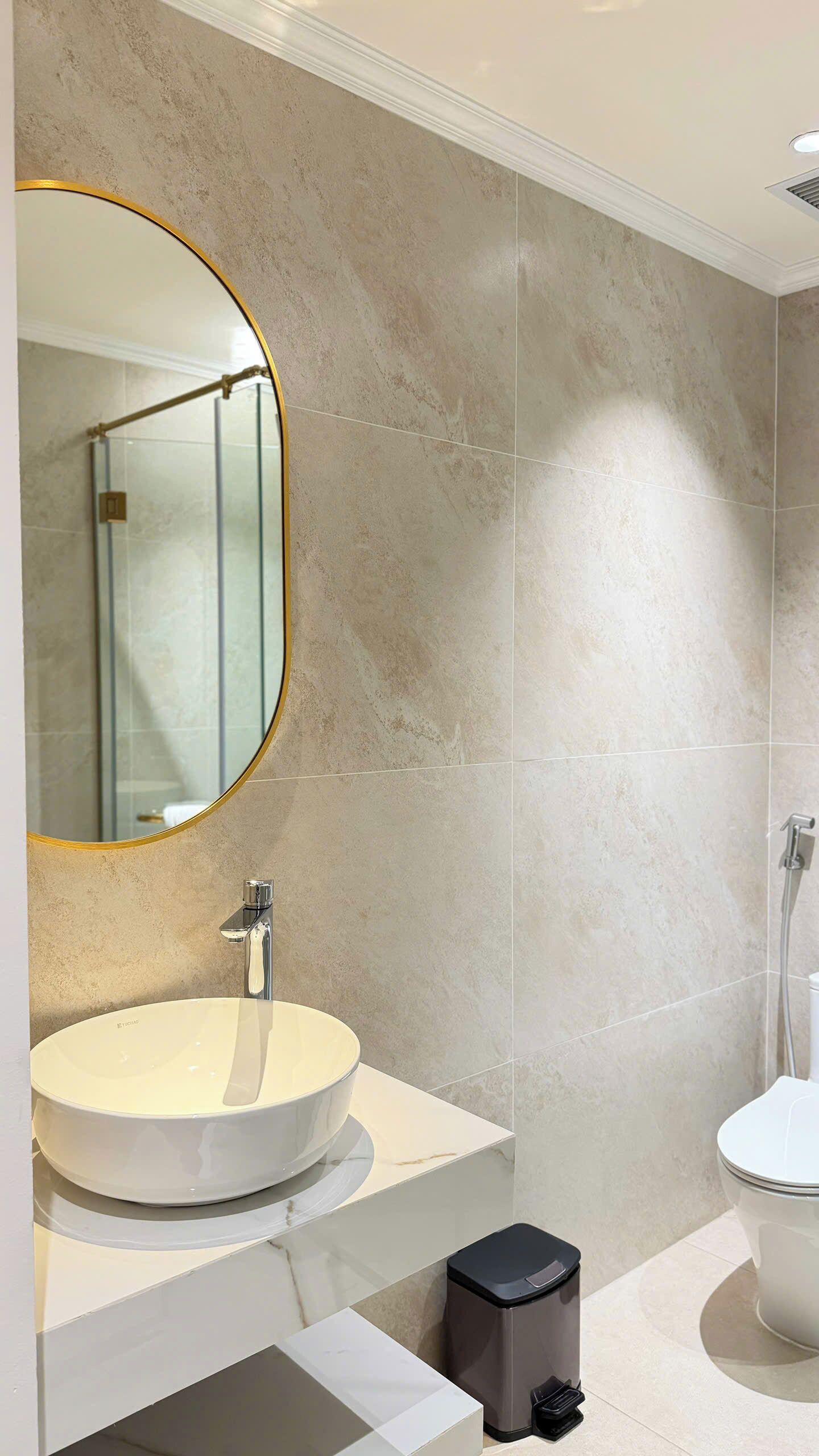 Un baño moderno con un lavamanos redondo, un inodoro y un cubo de basura.