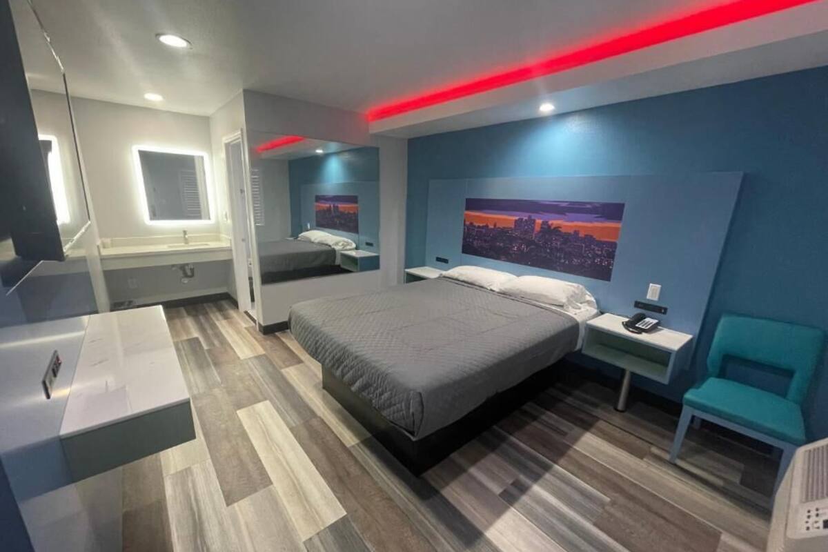 Una habitación de hotel moderna con una cama grande, mesitas de noche, un escritorio y una silla.