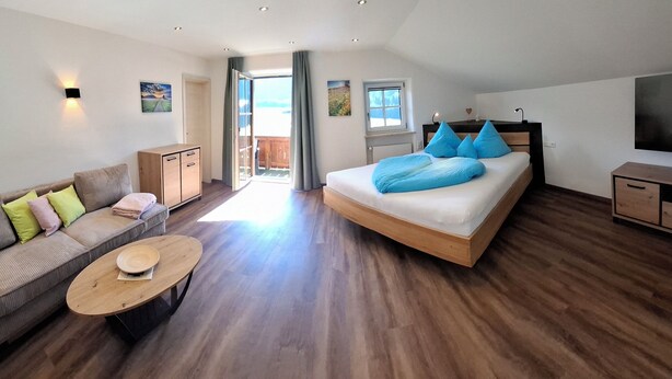 Ein modernes Schlafzimmer mit Bett, Sofa, Fernseher und Holzboden.