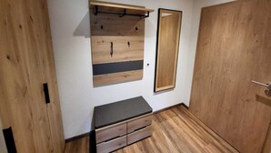 Ein Zimmer mit einem Holzschrank, einer Sitzbank mit Schubladen und einem Spiegel an der Wand.