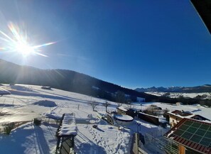 Schneebedeckte Landschaft mit blauem Himmel und Bergen im Hintergrund.