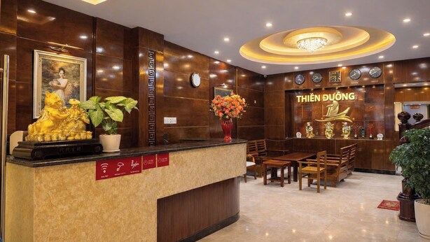 A hotel reception area with a wooden reception desk, a clock, and a 'THIEN DUONG' sign. - Thien Duong Hotel Hue (Hue)