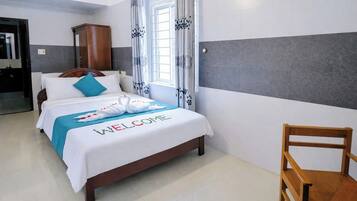 A hotel room with a bed, a wooden chair, and a wardrobe.