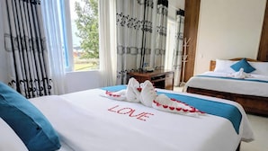 A hotel room with two beds, one with a swan decoration and the word "LOVE" on the bedspread, and a view of trees outside. - Thien Duong Hotel Hue (Hue)