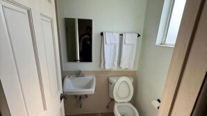 A bathroom with a toilet, sink, and a mirror. - El Rancho Motel - Pasadena (Pasadena)