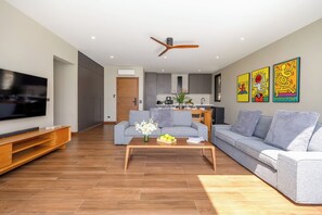 A modern living room with a flat-screen TV, grey sofas, a wooden coffee table, and a ceiling fan. - Villa Tenament 3BR at Chaweng Noi Hills (Ko Samui)