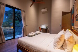 A modern bedroom with a large bed, a desk, and a chair, a ceiling fan, and a window with curtains. - Villa Tenament 3BR at Chaweng Noi Hills (Ko Samui)