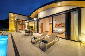 A modern hotel with a pool, outdoor seating, and a well-lit interior. - Villa Tenament 3BR at Chaweng Noi Hills (Ko Samui)