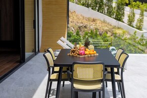 Un comedor con una mesa dispuesta para cuatro, rodeado de sillas de mimbre, y una bandeja con fruta y frutos secos sobre la mesa.