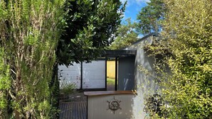 A compact, modern cabin with a wooden deck, surrounded by dense greenery. - Cozy 1 bedroom unit nestled in a lush sub tropical garden located in Kerikeri. (Kerikeri)