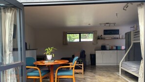 A modern living space with a dining area, kitchen, and a sleeping area with a bunk bed. - Cozy 1 bedroom unit nestled in a lush sub tropical garden located in Kerikeri. (Kerikeri)
