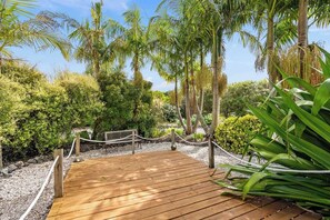 A wooden deck surrounded by lush greenery and palm trees.