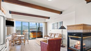 Ein modernes Wohnzimmer mit Kamin, einer Couch, einem Essbereich und Blick auf die Berge.