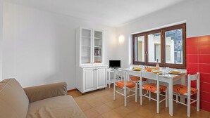 Ein kompakter Wohnraum mit Küchenzeile, Essbereich und einer Couch.