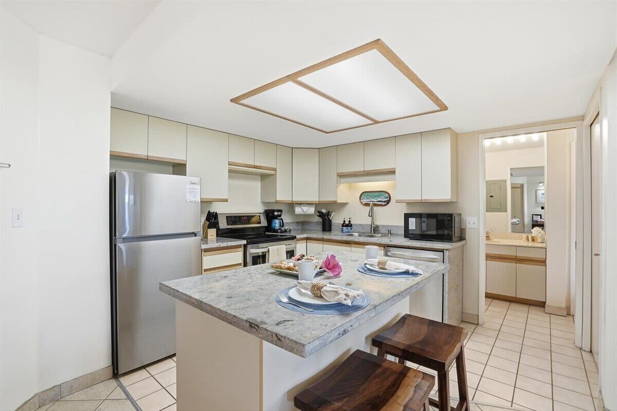 Una cocina moderna con una isla central, electrodomésticos de acero inoxidable y una zona para desayunar.