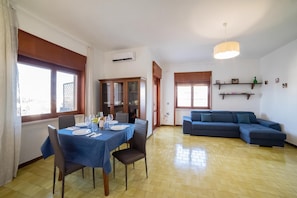 A dining area with a table set for four, a blue sofa, and a large window with a view.