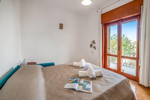 A hotel room with a large bed, a window with a view, and a magazine on the bed.