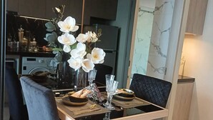 Ein Essbereich mit einem Glastisch, schwarzen Stühlen und einer Vase mit weißen Blumen.