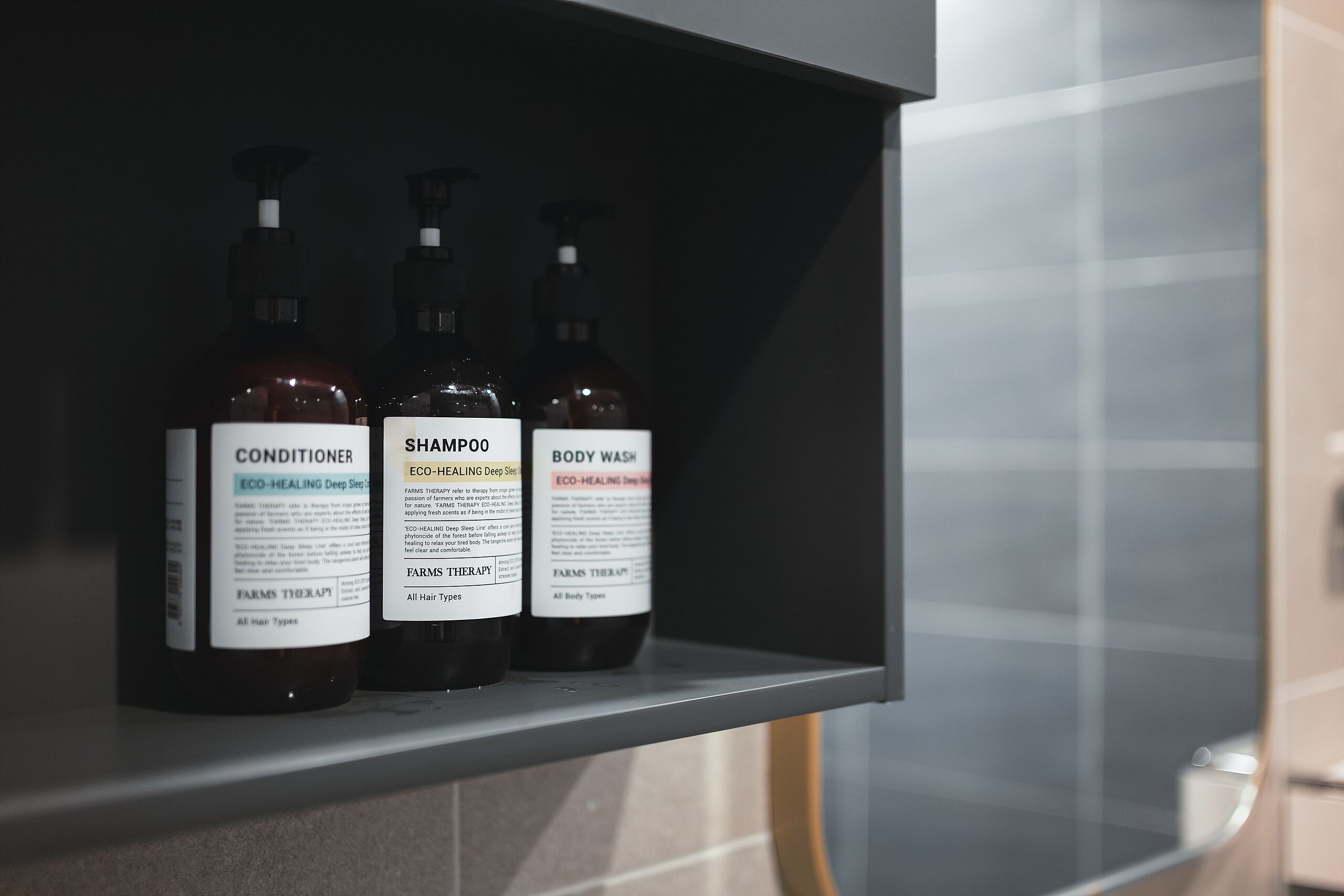 A shelf with three bottles of hair care products.