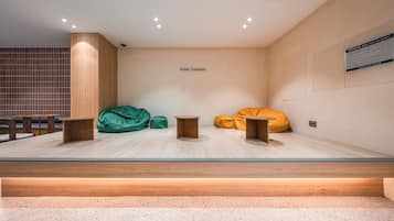 A modern hotel lobby with a seating area featuring green and yellow bean bags, wooden tables, and a wooden partition wall.