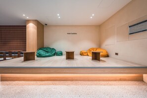 A modern hotel lobby with a seating area featuring green and yellow bean bags, wooden tables, and a wooden partition wall. - Hotel Coolstay Gimcheon (Gimcheon)