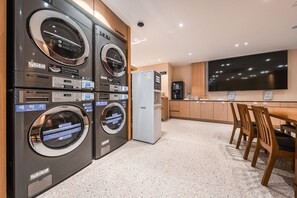 A laundry area with multiple washing machines and a commercial washer. - Hotel Coolstay Gimcheon (Gimcheon)