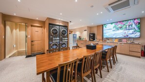 A hotel room with a wooden dining table, chairs, a television, a kitchen area, and a laundry room. - Hotel Coolstay Gimcheon (Gimcheon)