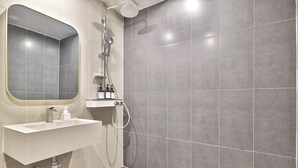 Un baño moderno con un lavamanos blanco, un espejo y una ducha.