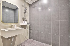 Une salle de bain moderne avec un lavabo blanc, un miroir et une douche.