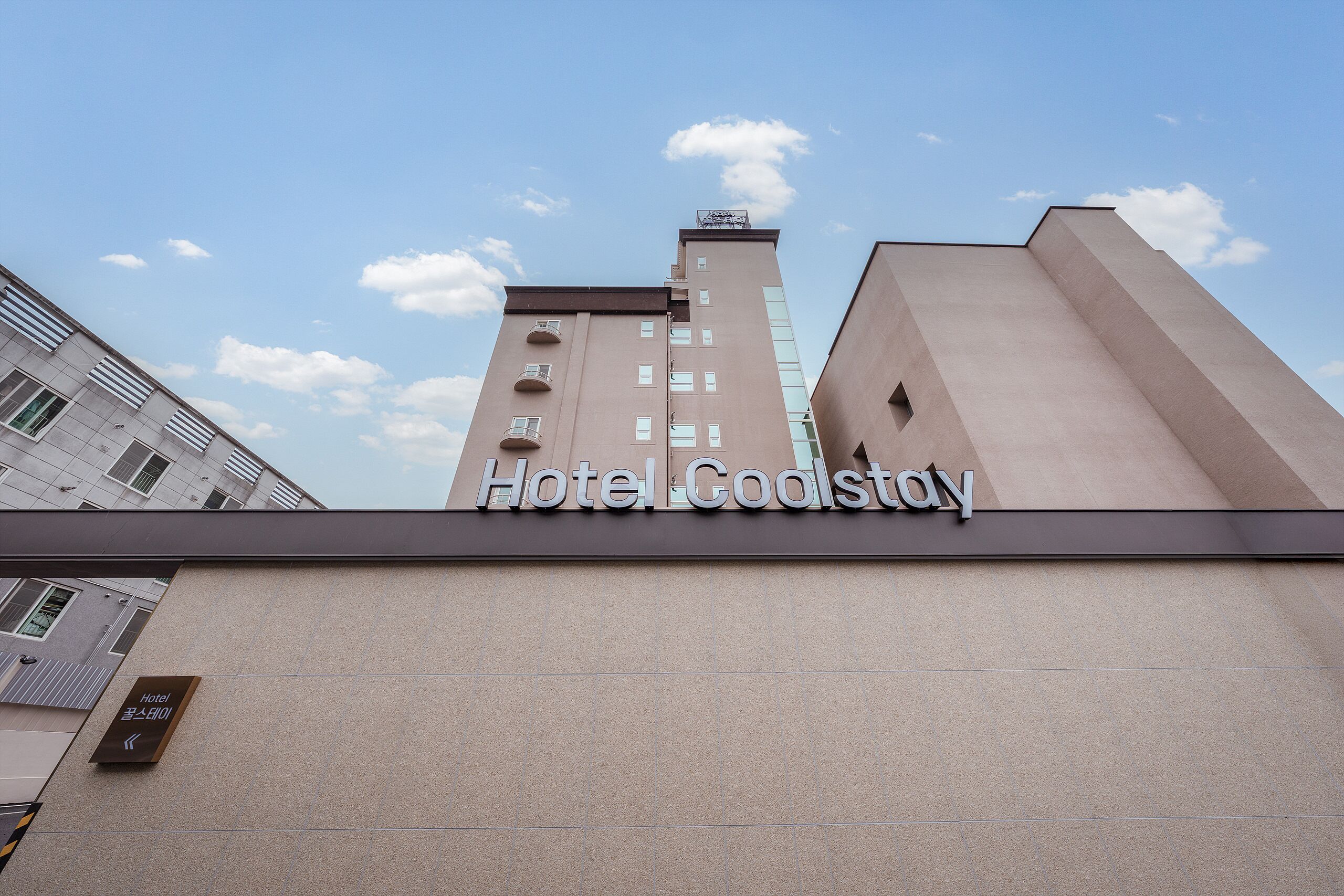 Un bâtiment sur lequel est apposée une enseigne indiquant « Hôtel Coolstay », ce qui permet d’identifier l’établissement.