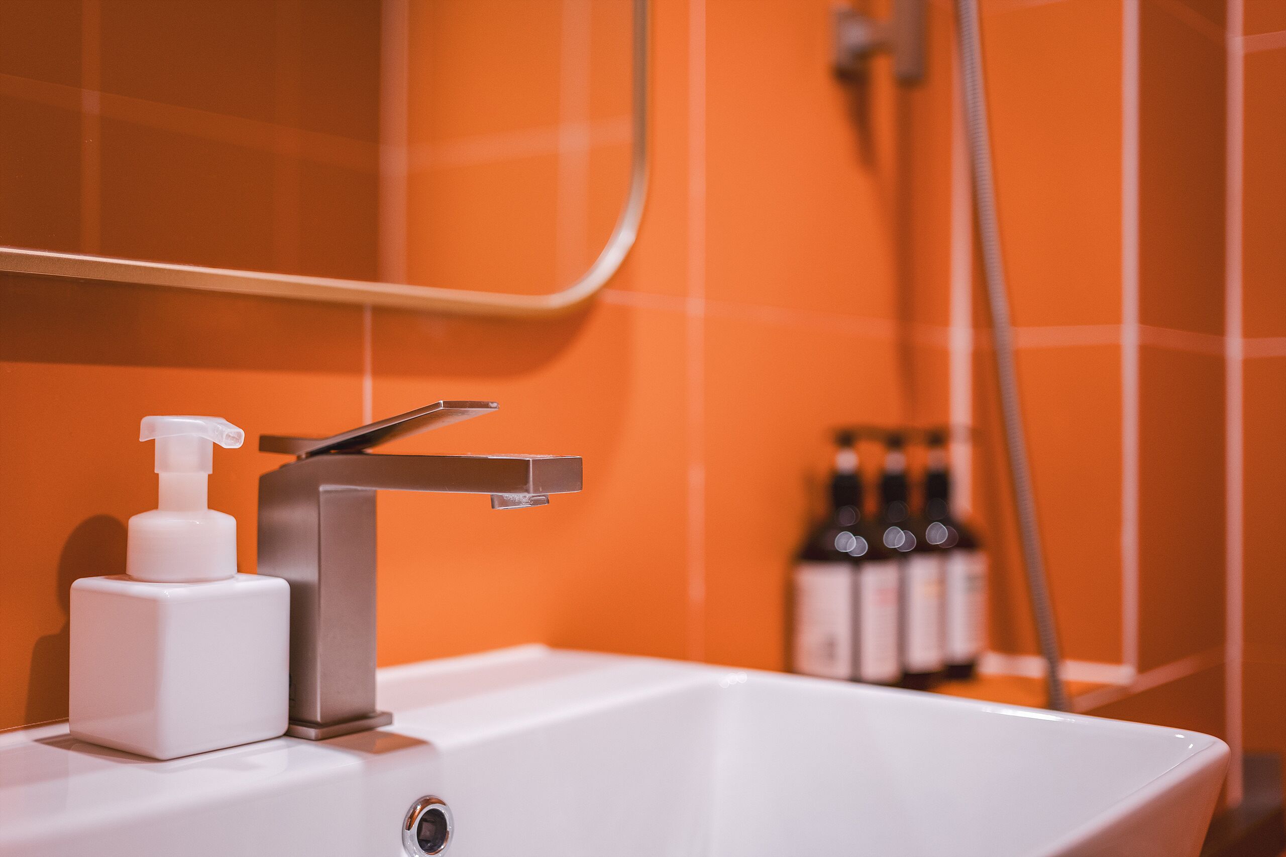 A bathroom sink with a modern faucet, a soap dispenser, and a mirror above it.