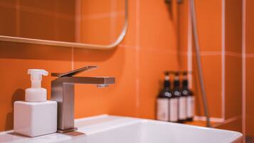 A bathroom sink with a modern faucet, a soap dispenser, and a mirror above it.