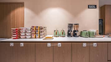 A breakfast station with various food items and kitchen appliances.