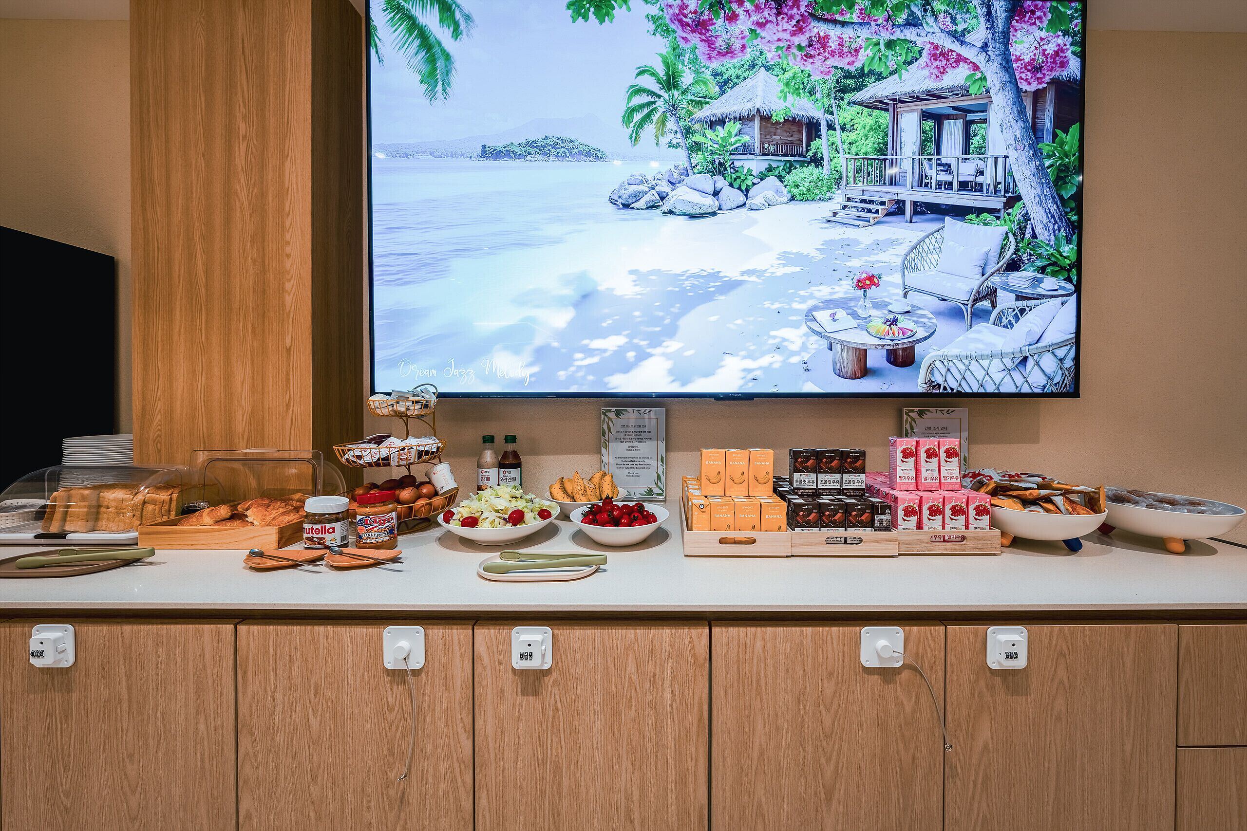 Un bufé de desayuno con diversas opciones de comida y una escena de playa tropical en la pared.