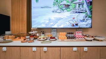Un bufé de desayuno con diversas opciones de comida y una escena de playa tropical en la pared.