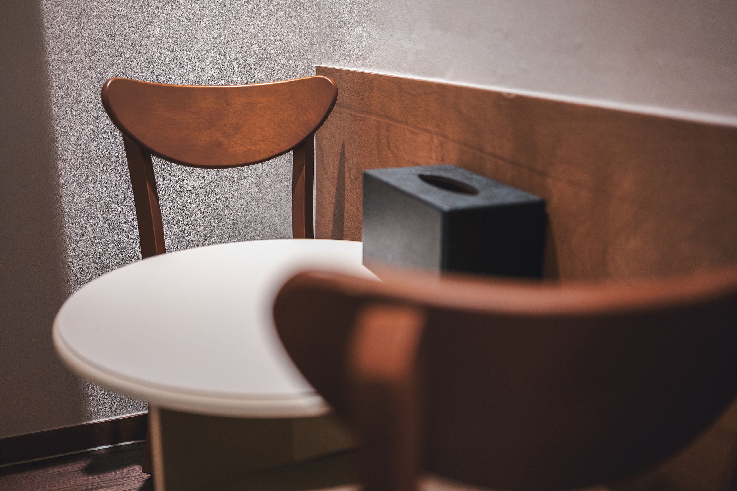 Een hoek van een kamer met een houten stoel en een witte tafel.
