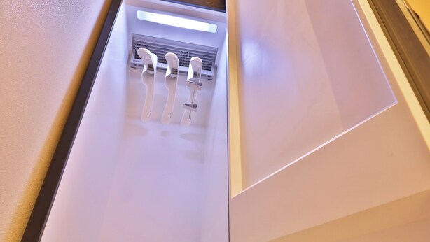 Una habitación de hotel moderna con un aire acondicionado integrado y un accesorio de iluminación en el techo.