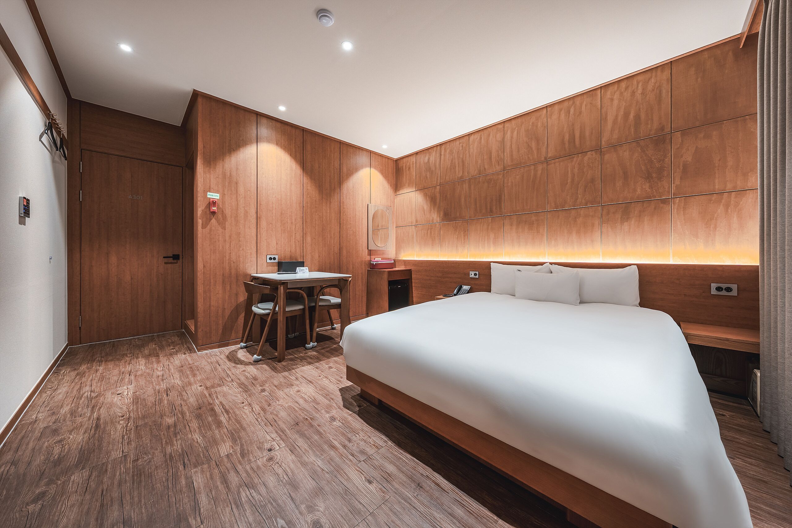Habitación de hotel con una cama grande, un escritorio con silla y un panel de pared de madera.