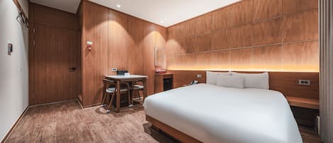 Habitación de hotel con una cama grande, un escritorio con silla y un panel de pared de madera.