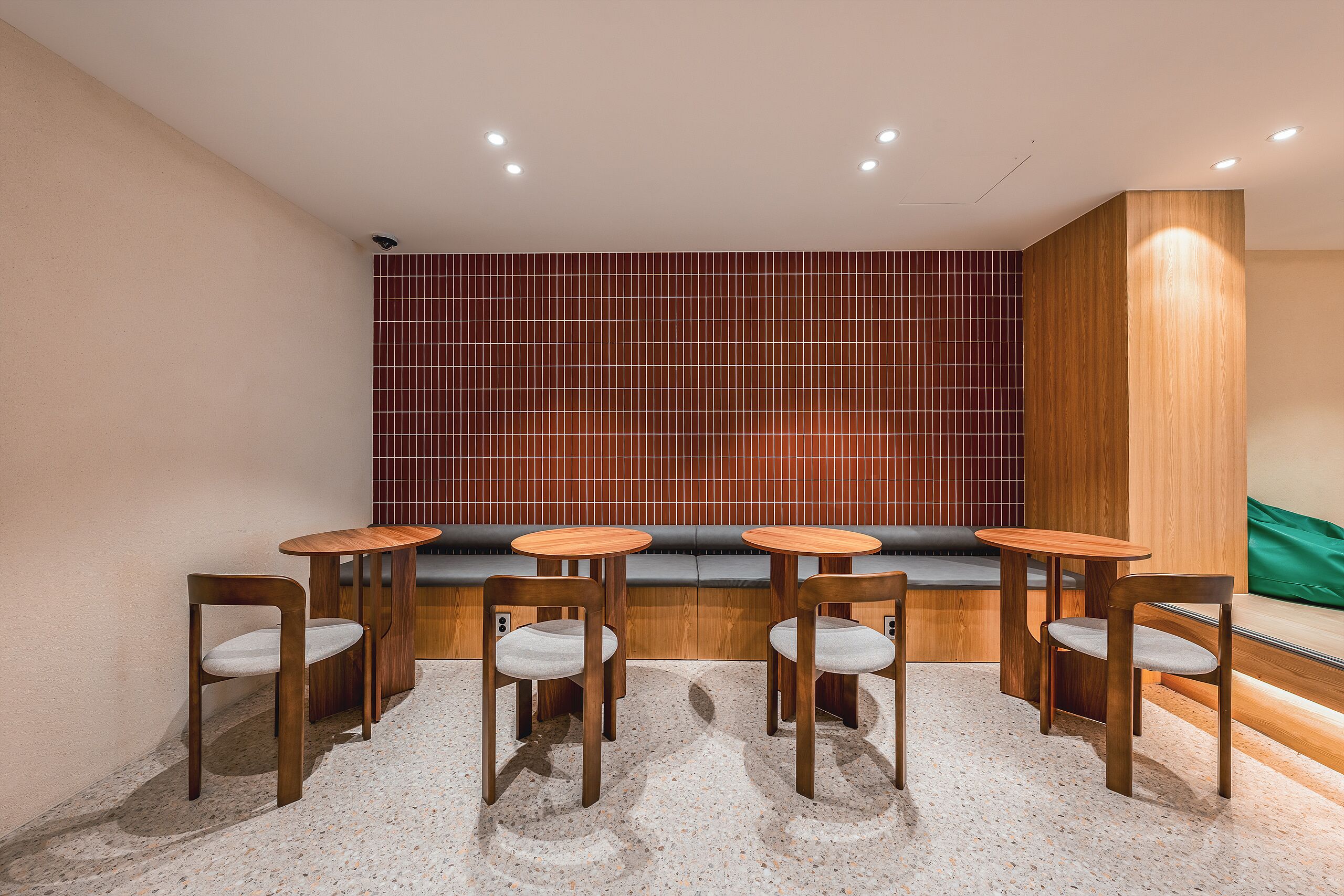 Un intérieur moderne avec un coin salon, des tables en bois et un mur orné de motifs.