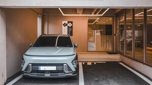 A parking area with a car, a sign for a front desk, and a building entrance. - Hotel Coolstay Gimcheon (Gimcheon)